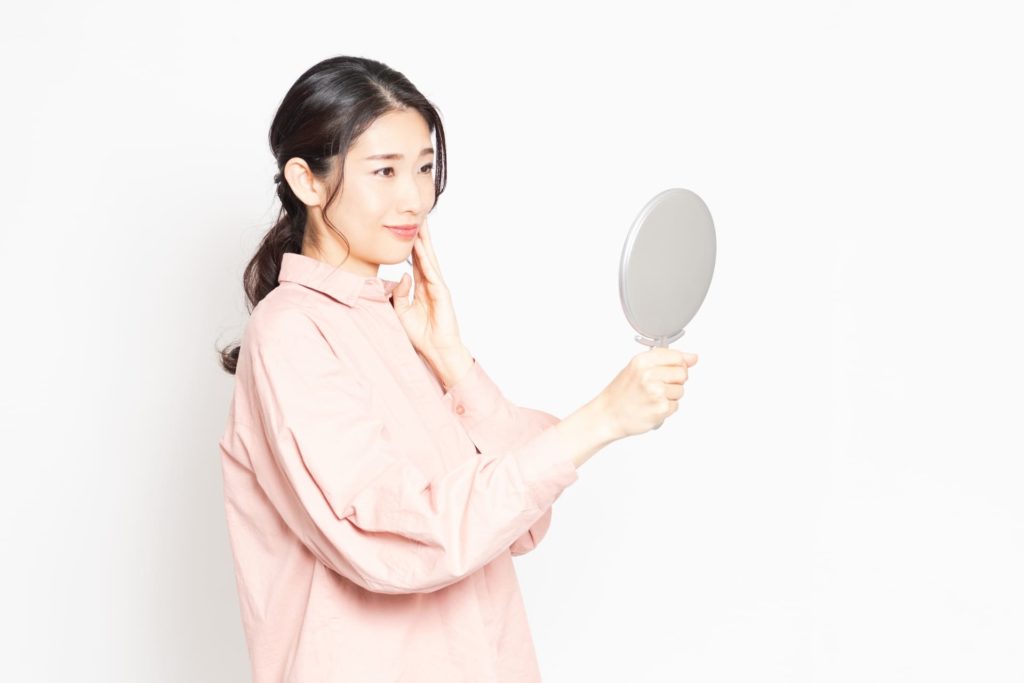 手鏡で自分の顔を見つめる女性