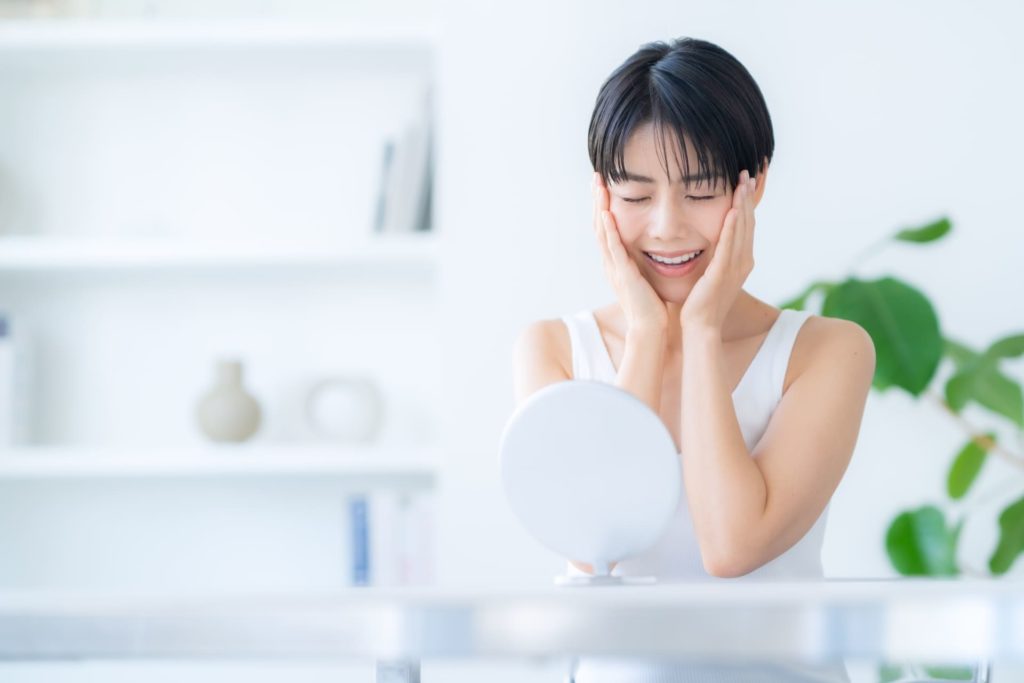 鏡を見ながら頬に手を当てる女性