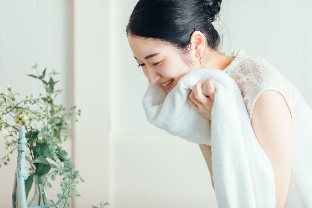 洗顔後タオルで顔を拭く女性