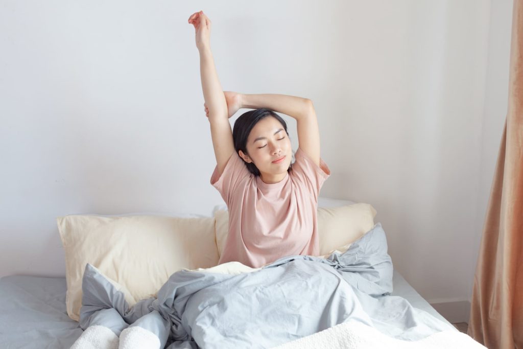ベッドでストレッチする女性
