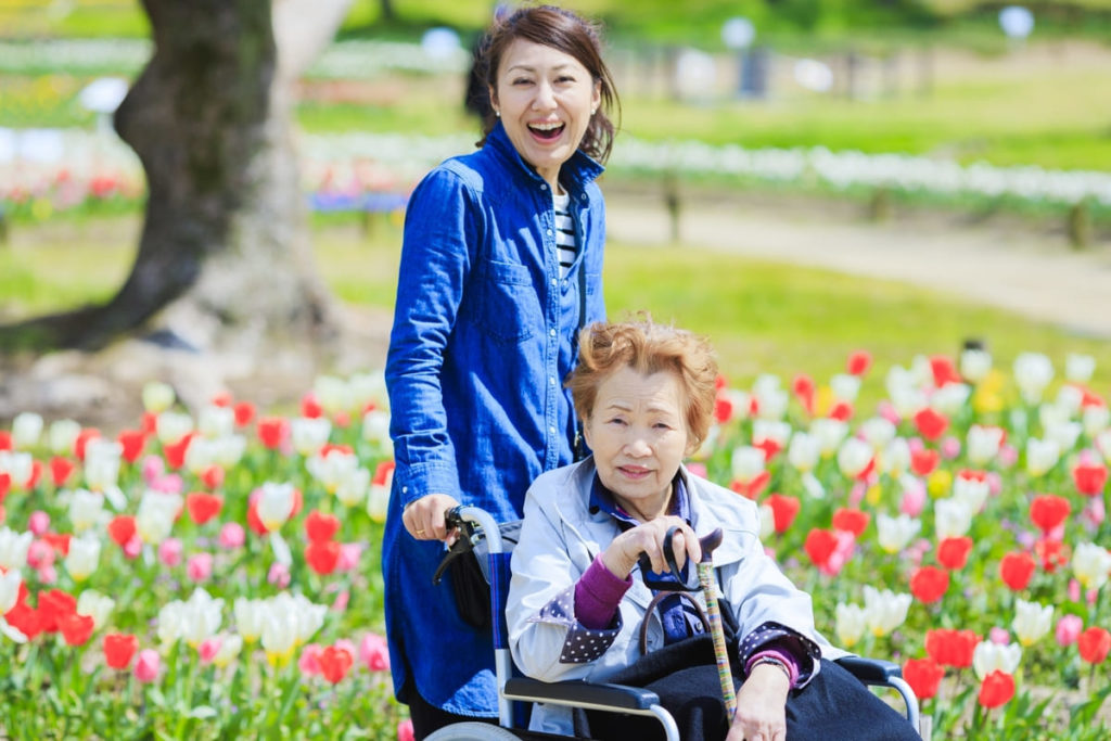 花畑で車椅子に乗った女性と車椅子を押す女性