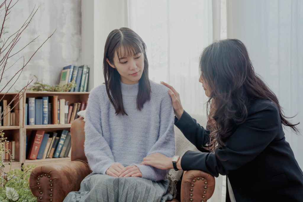 座る女性の方に手を置いて寄り添う女性