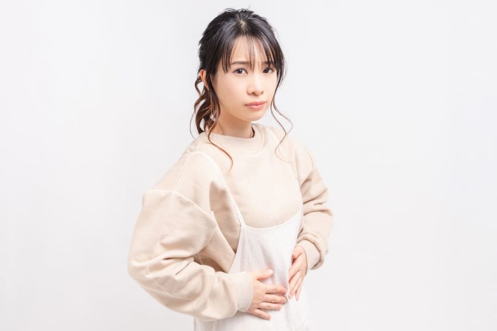 お腹に手を当てる若い女性
