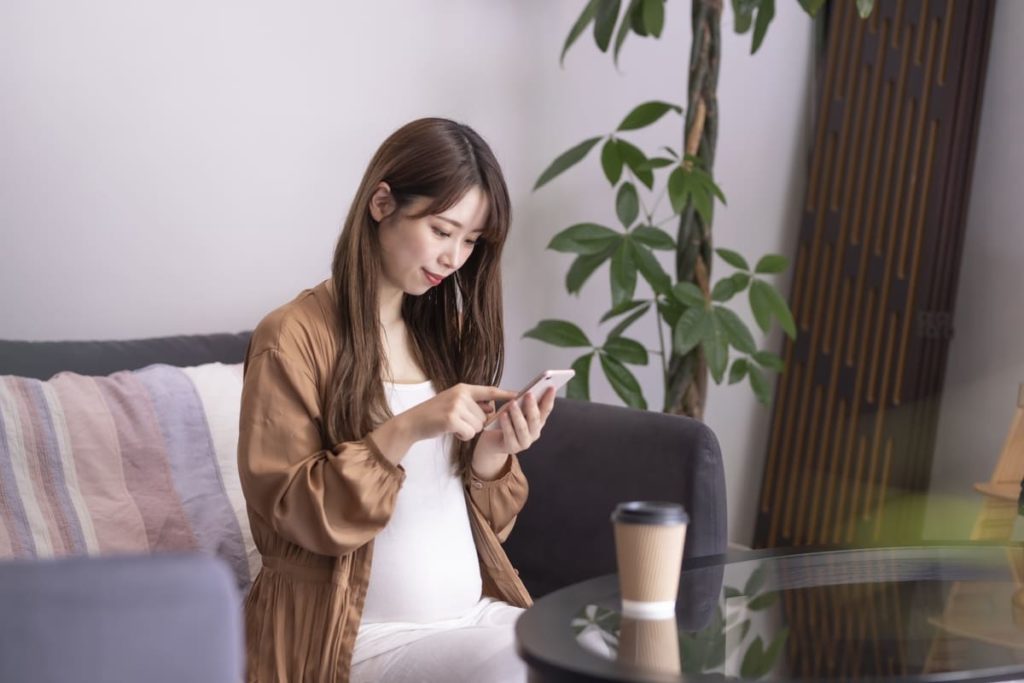 スマートフォンを操作する妊娠初期の女性