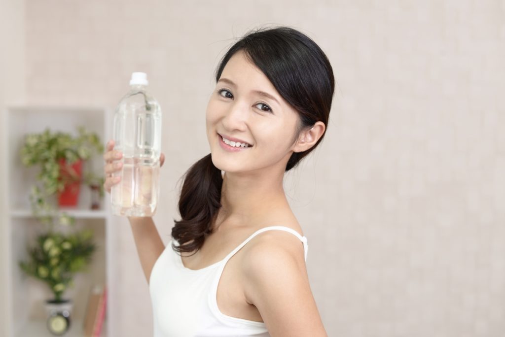 ペットボトルの水を飲む女性