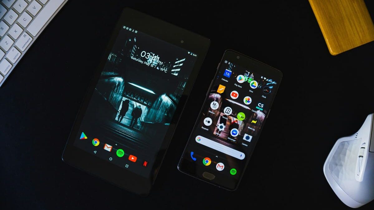 A tablet and smartphone placed next to a keyboard and a VR headset, with the devices' screens filled with various app icons.