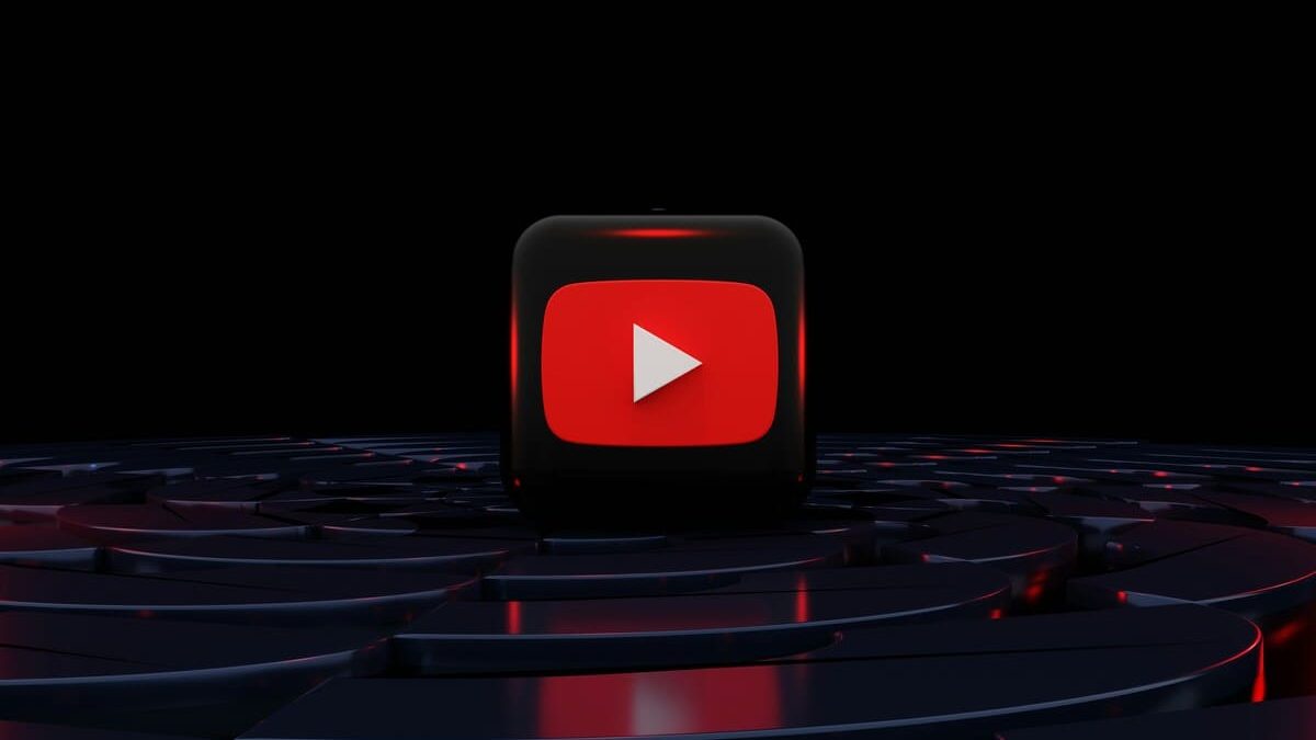 A 3D black cube with the red YouTube play button symbol on it, set against a dark, reflective surface, with red highlights, creating a dramatic effect.