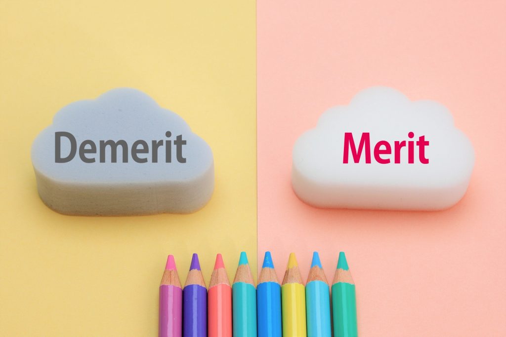 「Demerit」と「Merit」と書かれた雲型のオブジェとカラフルな色鉛筆の画像。