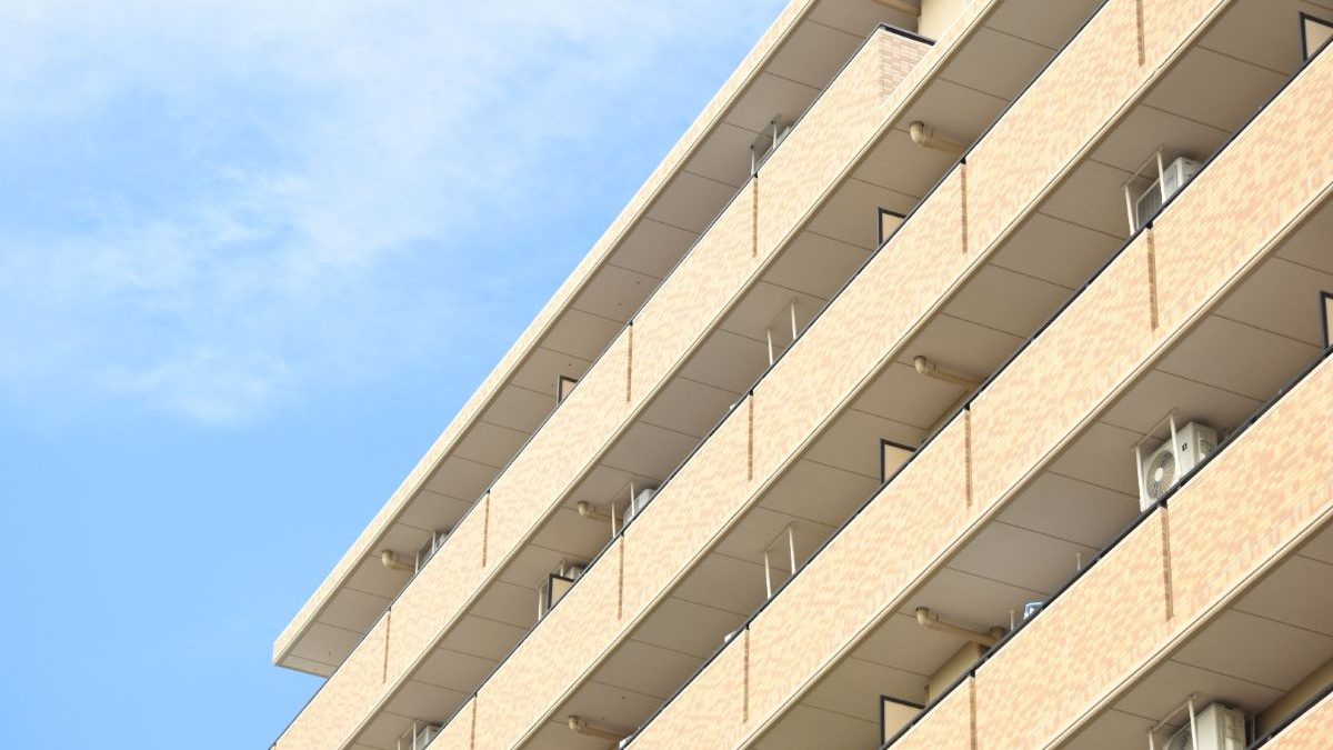 Exterior view of a modern apartment building under a blue sky.