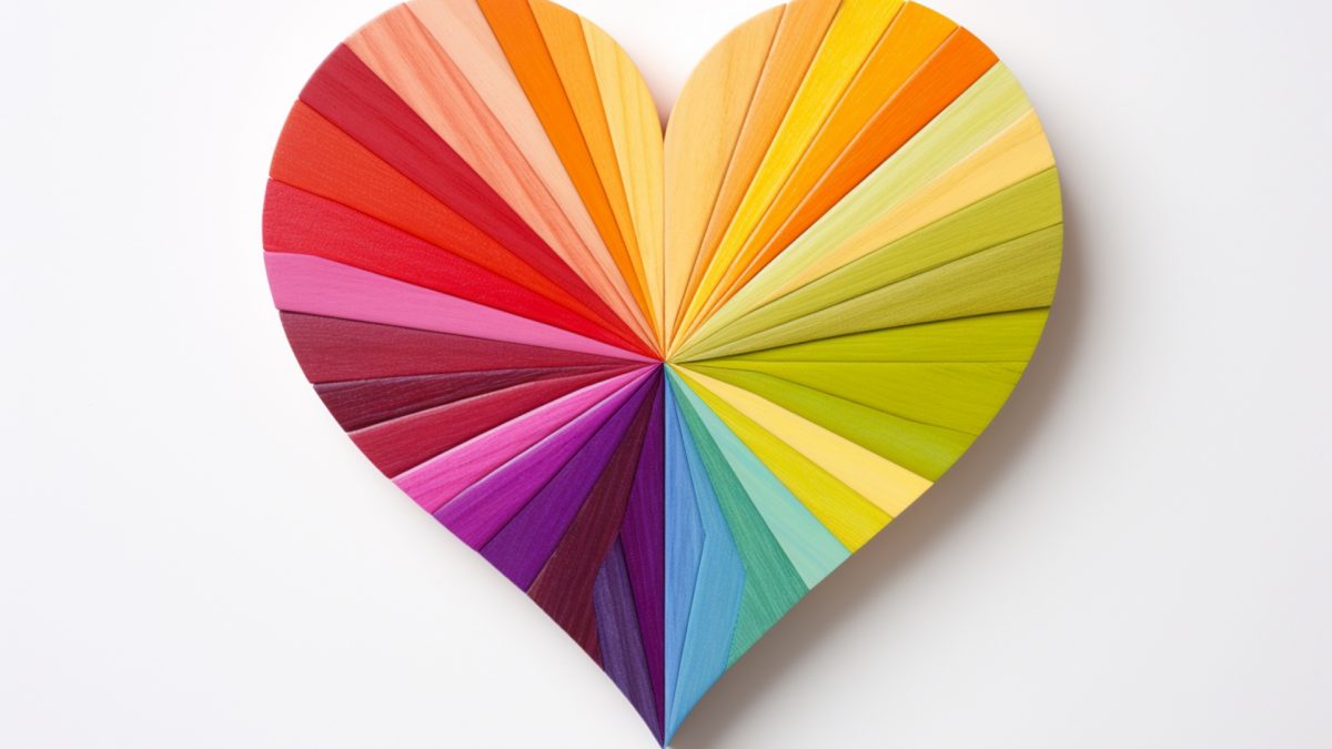 A colorful heart-shaped object made of wooden pieces arranged radially in various shades of red, orange, yellow, green, blue, and purple.