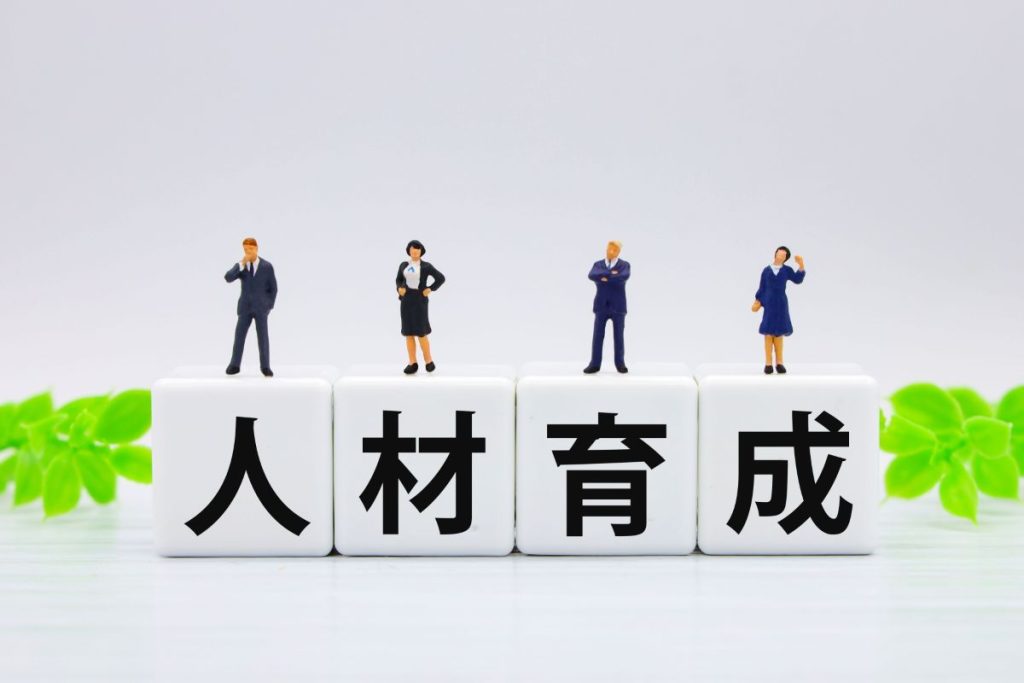 「人材育成」と書かれたブロックとビジネスパーソンのフィギュアの画像。
