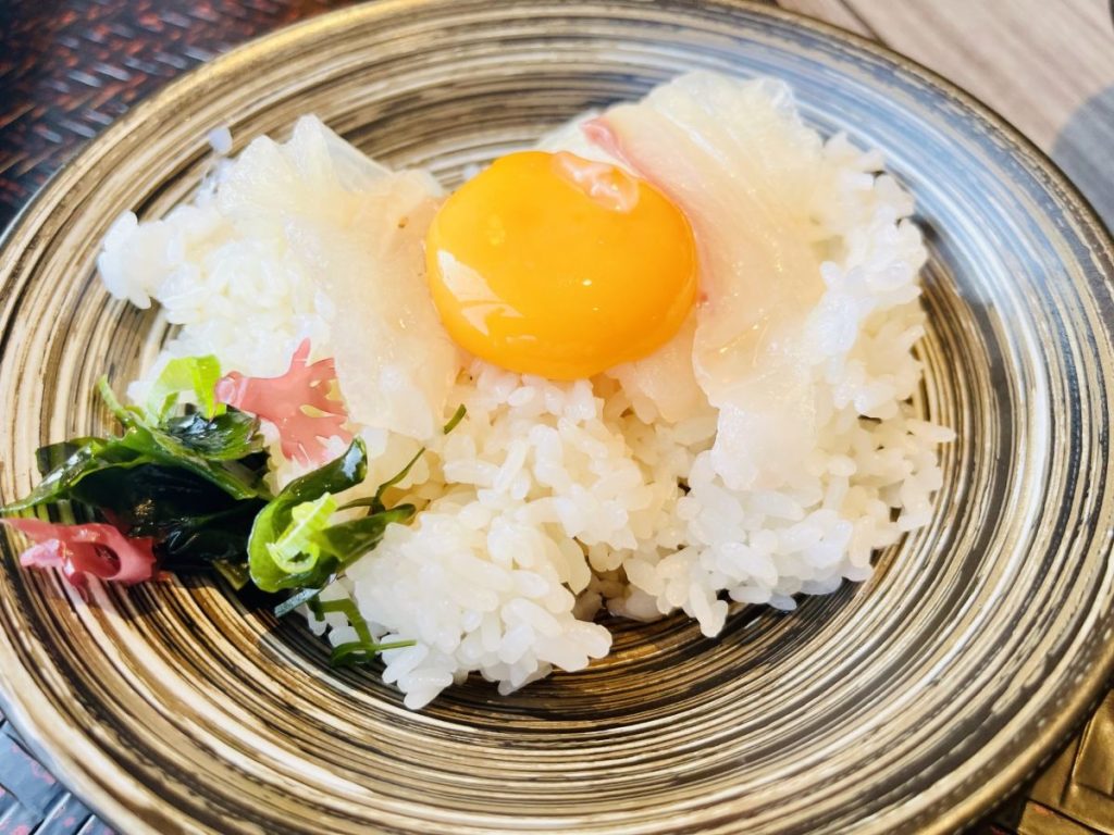鯛の刺身と卵黄をご飯にのせた、宇和島の鯛めしの画像。