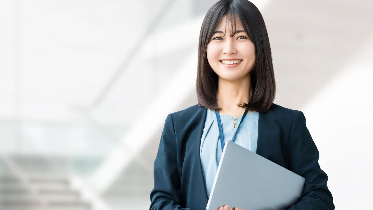 Young female office worker smiling with a laptop in a modern business environment