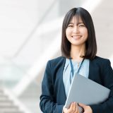 Young female office worker smiling with a laptop in a modern business environment