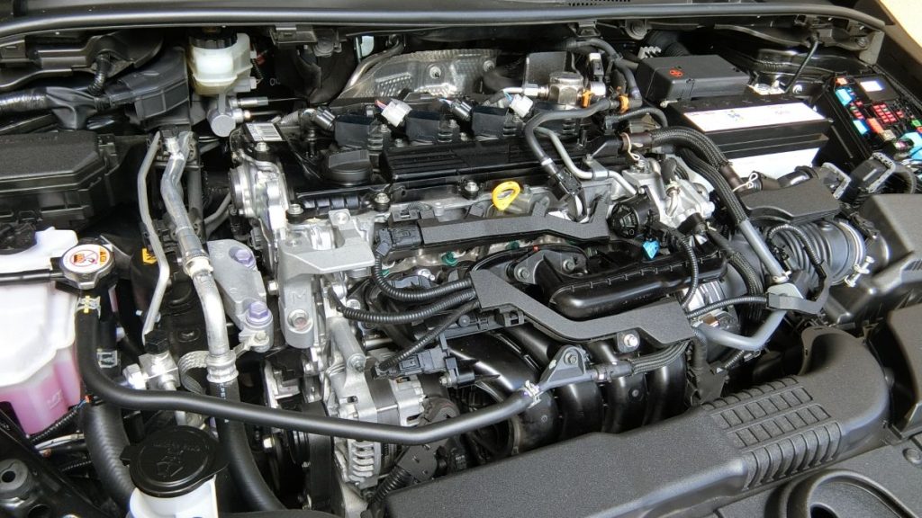自動車のボンネットを開けた状態で撮影されたエンジンルームのクローズアップ。エンジン本体や各種配管、バッテリー、冷却液タンクなどが細部まで鮮明に写っており、車のメンテナンスや構造説明に適した写真。