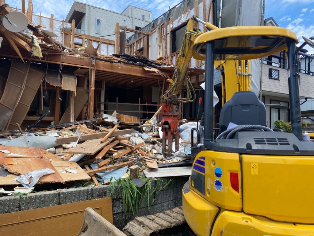 造家屋を解体する黄色いショベルカーの画像。