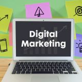 An image of a laptop displaying the words "Digital Marketing" on the screen, with colorful sticky notes and icons in the background, symbolizing marketing strategies and creative ideas.