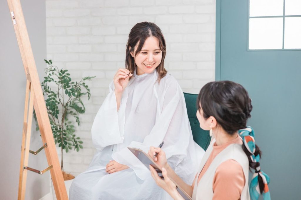 美容室でカウンセリングを受けているお客様と美容師の打ち合わせ風景。