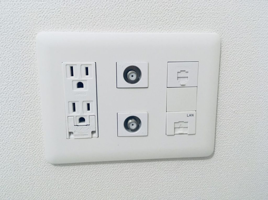 壁に設置されたコンセント、テレビ端子、電話端子、LANポートの写真。