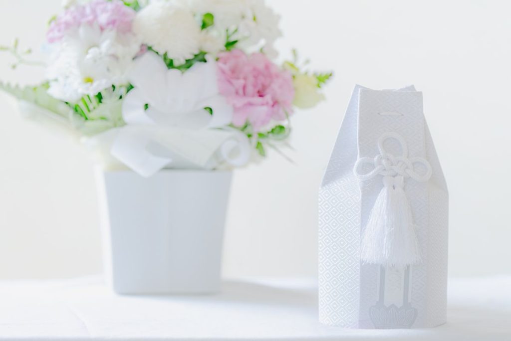 白い覆いに包まれたペットの遺骨と、優しい色合いの供花。シンプルで清らかな空間を表現している。