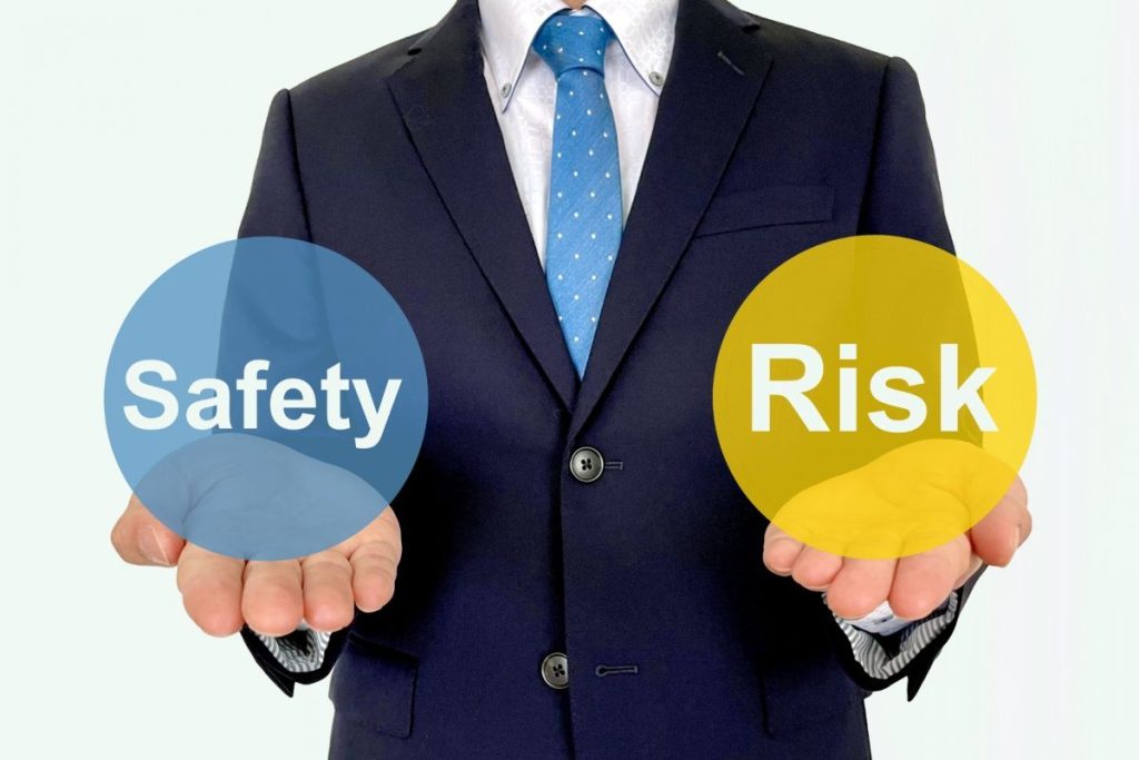 ビジネスマンの手のひらに「safety」と「risk」の文字が浮かんでいる。リスク管理の注意点を喚起するイメージ。