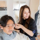 A hairdresser is styling a customer's hair during a haircut at a salon.