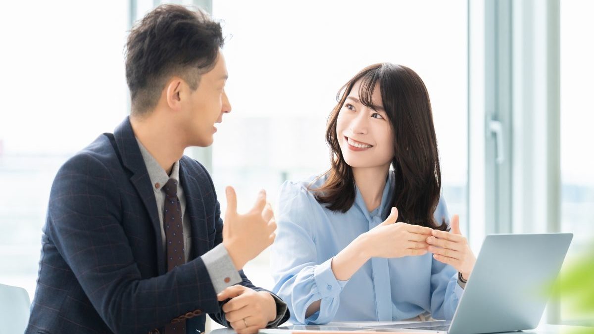 A business coach and client having a positive and engaging conversation in a bright office, representing a coaching session based on trust.