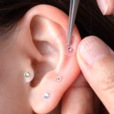 A close-up image of ear acupressure jewelry being gently applied, representing a self-care practice for beauty and health.