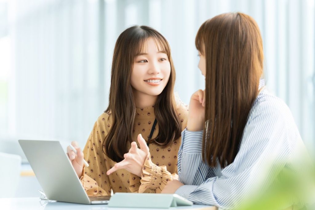 知識を共有しながら、ティーチング形式で学んでいる2人の女性。教える・教わる関係や対話による学習のイメージ。