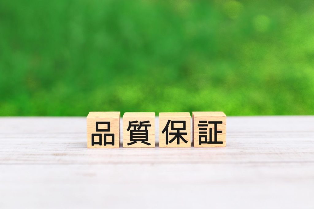  「品質保証」と書かれた木のブロック。信頼できる水素吸入機器の選び方や、安全性への配慮を象徴するイメージです。
