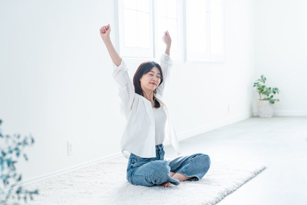 明るい部屋で気持ちよくストレッチをする女性。水素ガス吸入によって心身が整い、すっきりとした朝を迎える様子を表現しています。