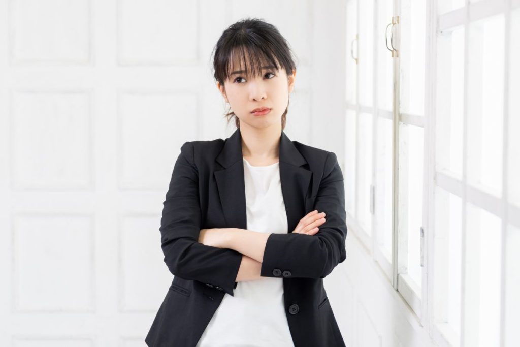 モヤモヤした感情を抱え、立ち止まっている女性。探究分析学®︎を必要とする、「自分でも気づいていない本音」と向き合う前の状態を象徴しています。