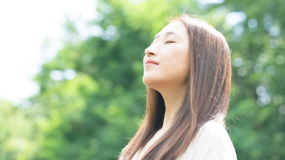 A woman taking a deep breath in nature, symbolizing inner reflection and listening to one’s inner voice—key aspects of TANKYU Analysis®︎.