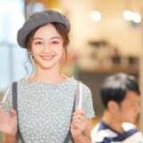 A young hairstylist smiling while holding scissors and a comb in a salon, representing a friendly and approachable junior hairstylist.