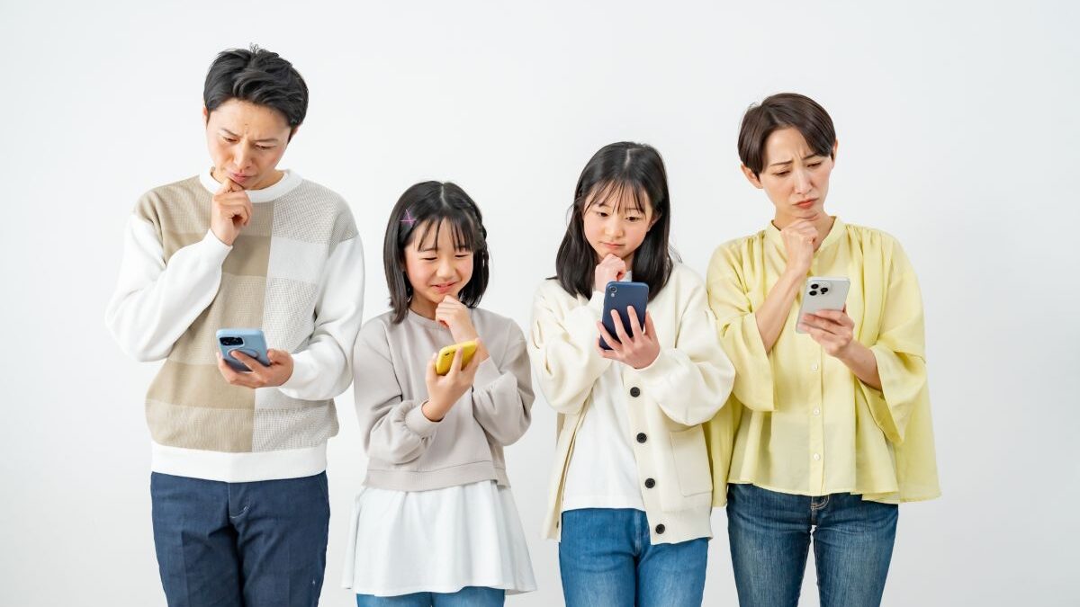 A family of four looking at their smartphones with thoughtful expressions. Represents concerns about internet setup or choosing a broadband service.