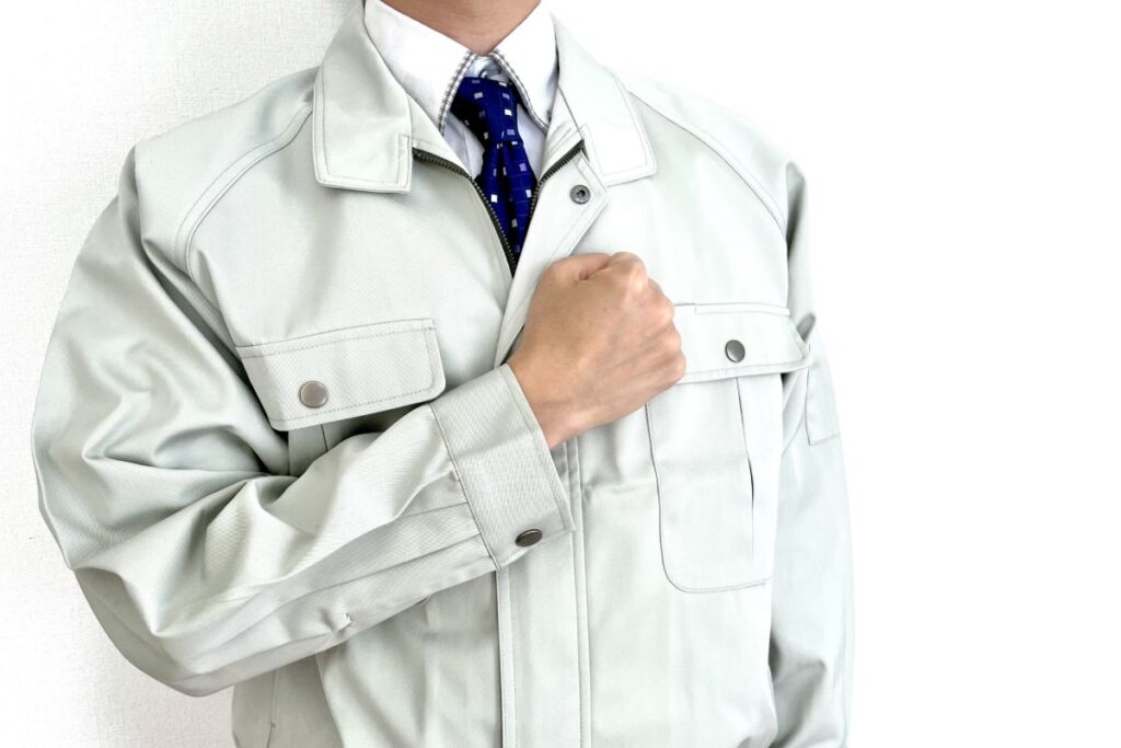 胸に手を当て、信頼と責任感を示す作業服姿の施工業者。