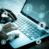 Hands typing on a laptop with network icons of people connected, representing information sharing and networking through social media.