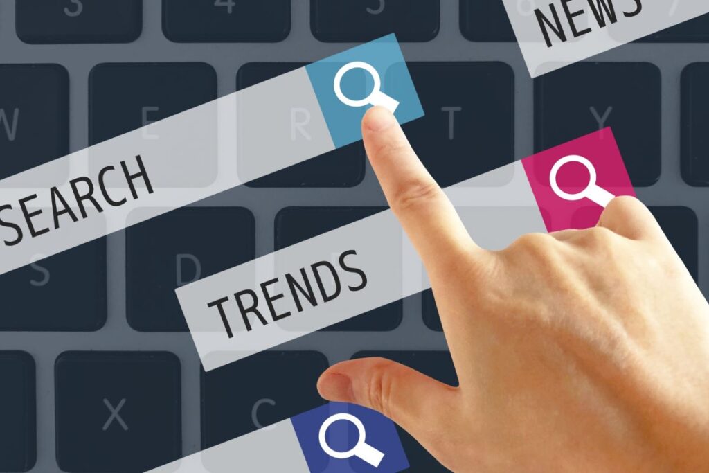 キーボード上で「SEARCH」「TRENDS」をタップする手、最新情報をリサーチするイメージ。