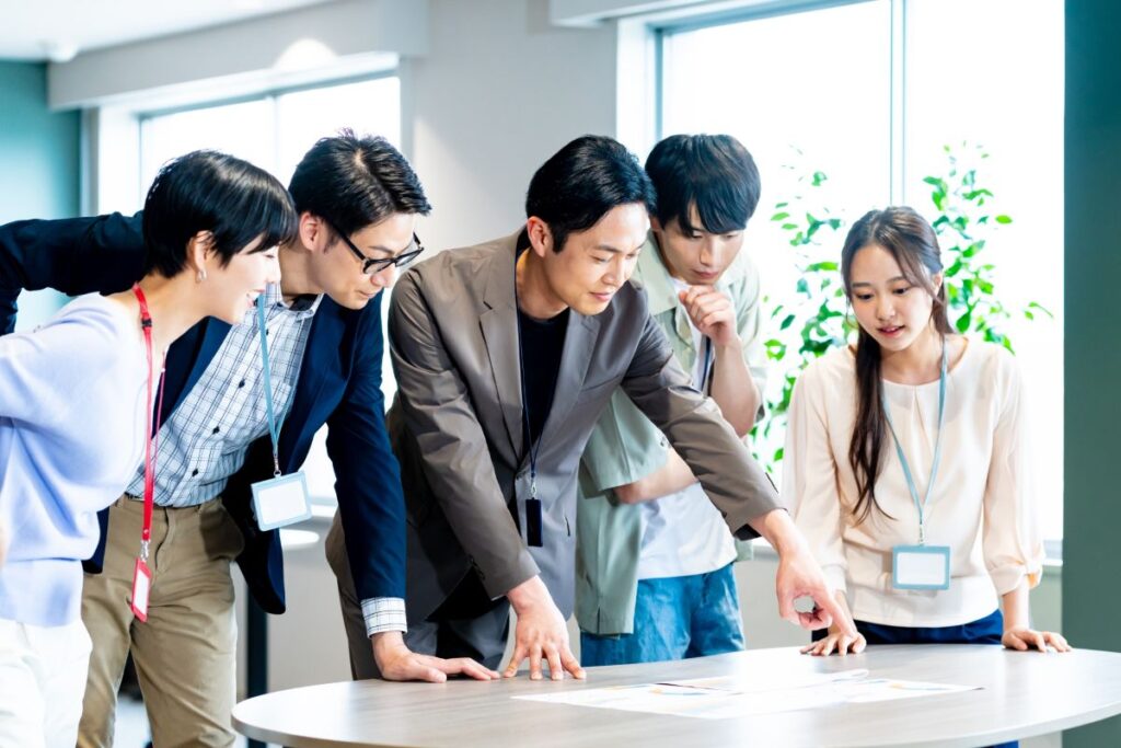 企業イベントの企画会議。複数の社員が資料を見ながら計画を練るシーン。