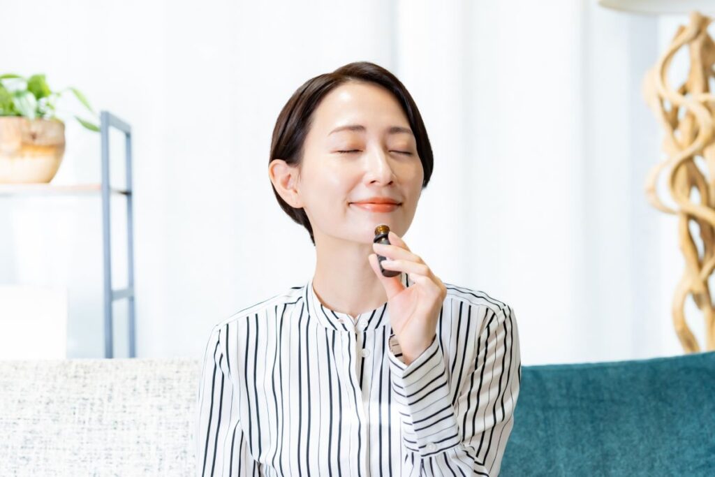 アロマオイルの香りを楽しむ女性。リラックスした表情が、心の安らぎと癒しの時間を表現している。