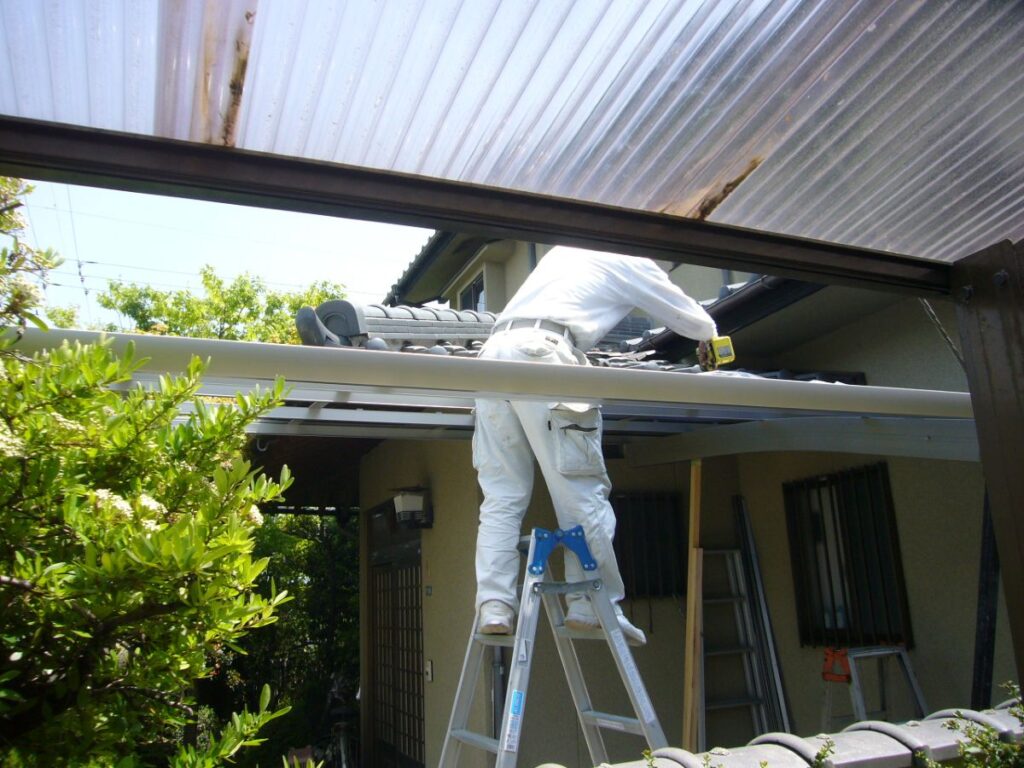 職人が脚立に上ってカーポートの解体作業を行っている様子。安全対策と専門技術の大切さを伝える写真。