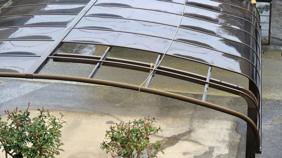A damaged carport with a bent roof, showing signs of deterioration or storm damage.