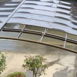 A damaged carport with a bent roof, showing signs of deterioration or storm damage.
