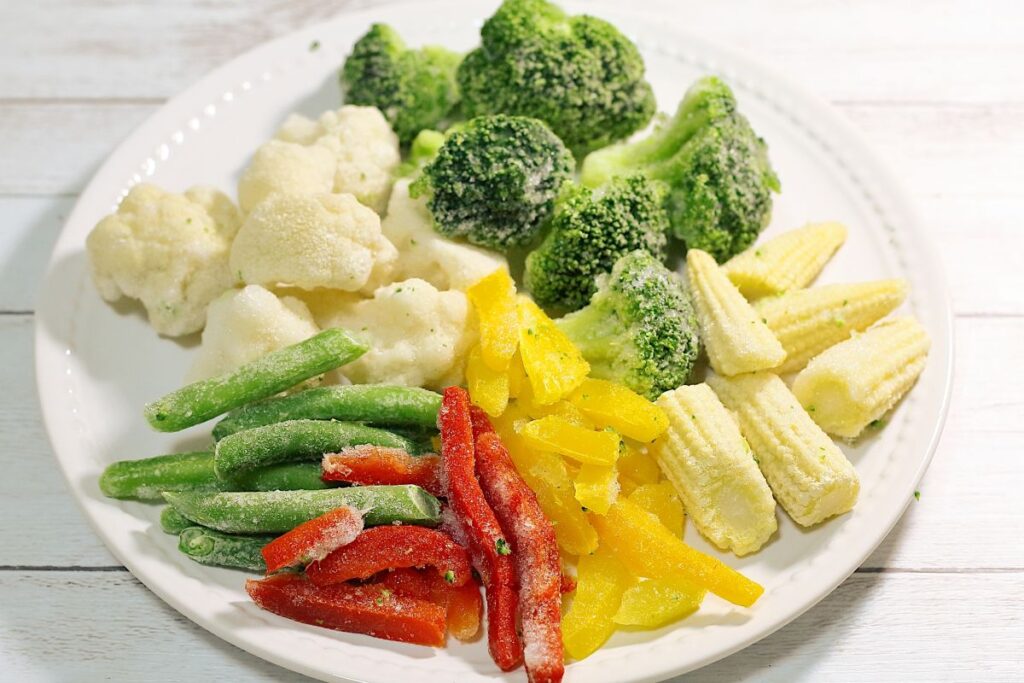 ブロッコリーやパプリカなど、色とりどりの冷凍野菜が皿に盛られた写真。忙しい中でも栄養を取れる自然派食品のイメージ。