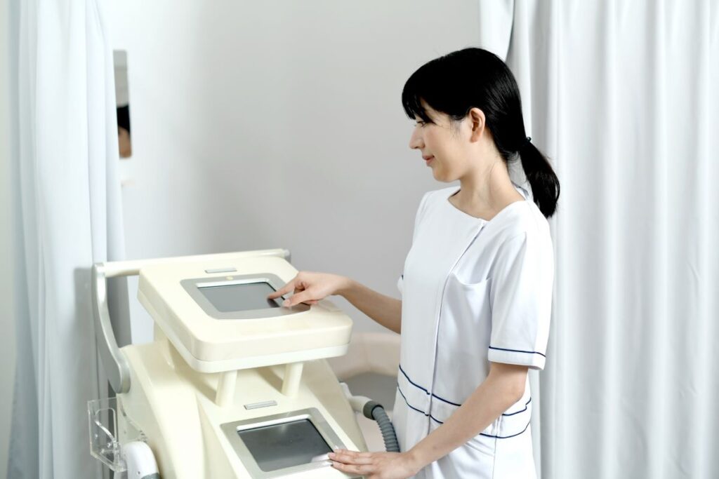 A staff member in a white uniform operating a hair removal device, representing a professional medical or salon hair removal service.