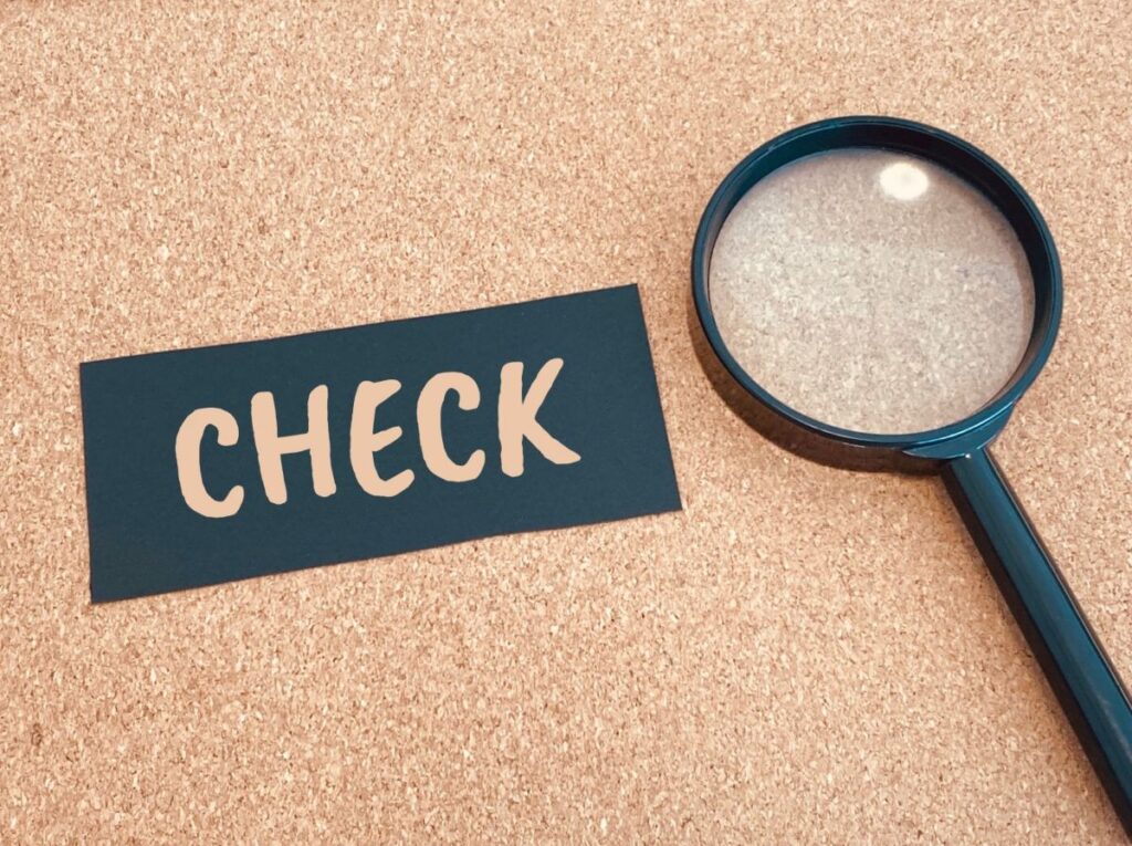 「CHECK」と書かれた紙と虫眼鏡の写真。中古トラック買取前に確認すべき重要事項を示すイメージ。