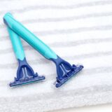 A photo of blue razors placed on a towel, representing shaving before men’s VIO hair removal treatment.