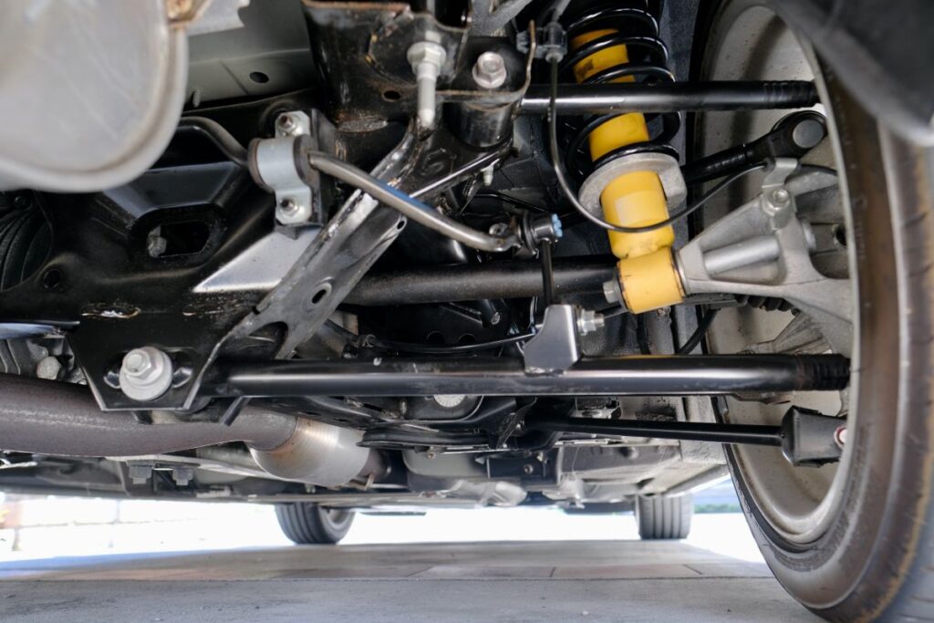車の下から見た足回りの構造。ショックアブソーバーやサスペンション部品がはっきり見えるメカニカルなイメージ。