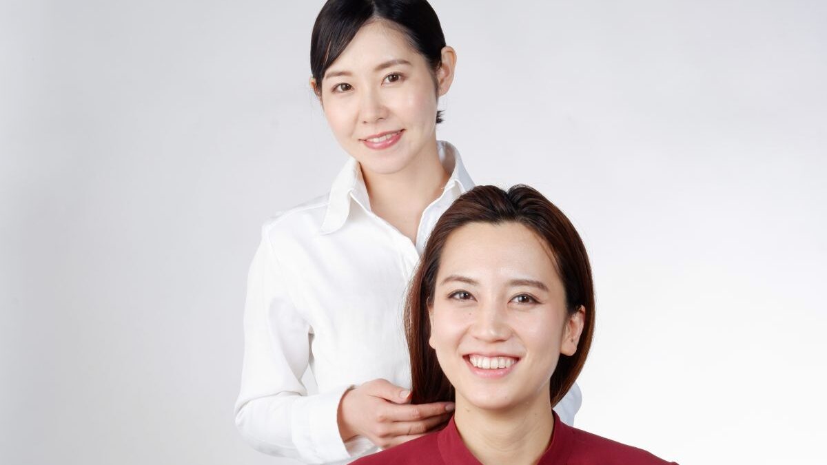 A hairdresser smiling while gently touching a client’s hair, representing trust, skill, and the professional art of creating beauty.
