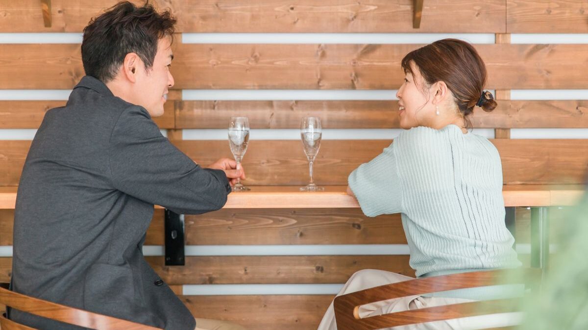 A couple in their 40s enjoying a conversation at a café, smiling warmly at each other in a relaxed atmosphere.